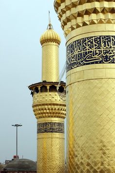 two tall gold and black buildings with arabic writing on them