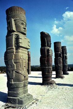 some very tall statues sitting in the sand