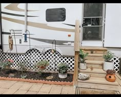 an rv parked in front of a house with potted plants