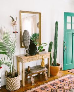 a room filled with lots of plants and a wooden table in front of a green door