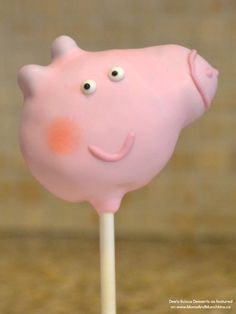 a pink pig lollipop with googly eyes on it's head sitting on a stick