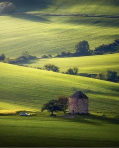 an old barn in the middle of a green field