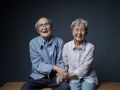 an older couple sitting on top of a wooden table