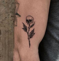 a skull and rose tattoo on the left arm, with one flower in it's center