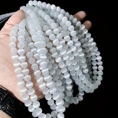 a person holding several white beads in their hand