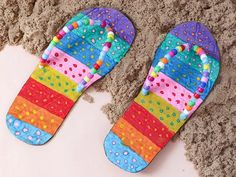 two pairs of colorful flip flops laying on the sand