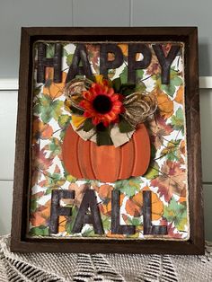 a wooden frame with a pumpkin and flower on it that says happy fall in the center