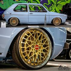 an old blue car with gold rims parked in front of a graffiti covered wall