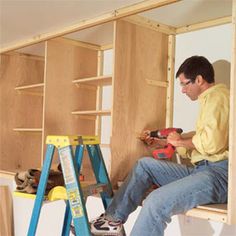 a man sitting on top of a step ladder in a room filled with construction supplies