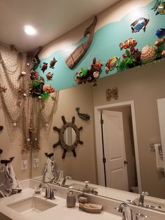 a bathroom decorated with fish and marine life on the wall, along with two sinks