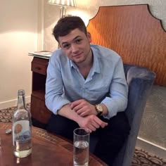 a man sitting at a table with two bottles of water in front of him and an empty glass on the table