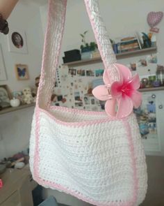 a crocheted purse with a pink flower hanging from it's side,