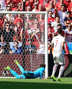 the soccer player is sliding into the goal to try and block the ball from him