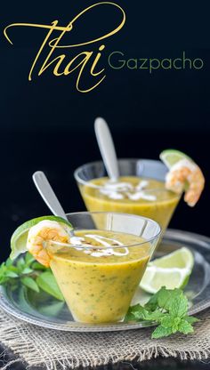 two small bowls filled with soup and garnished with cilantro, lime and shrimp