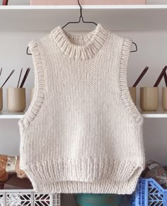 a knitted sweater hanging on a rack in front of some vases and other items