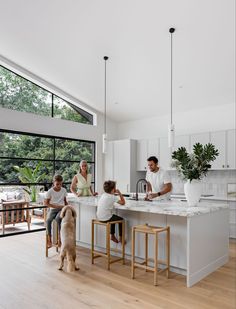 a group of people sitting at a kitchen counter with a dog in front of them