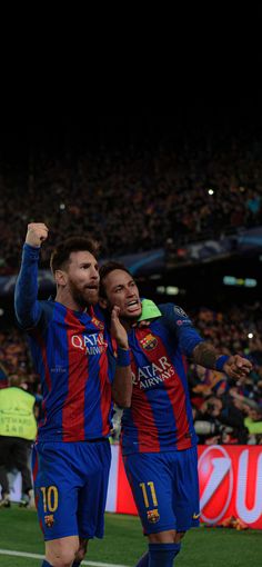 two soccer players are congratulating each other on the field in front of an audience