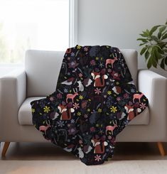 a couch with a blanket on top of it in front of a window and potted plant