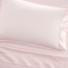 a white bed with pink sheets and pillows