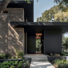 the front entrance to a modern house with black brick walls and steps leading up to it