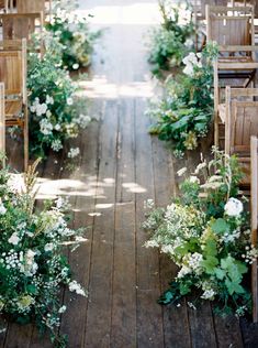 the aisle is lined with wooden chairs and flowers