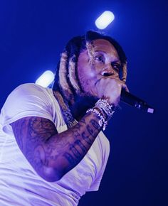 a man with dreadlocks on his head holding a microphone