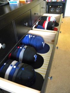 several hats sit in the drawers of a dresser