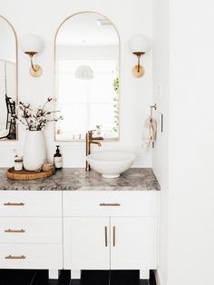 a bathroom with marble counter tops and two sinks in front of an oval mirror on the wall