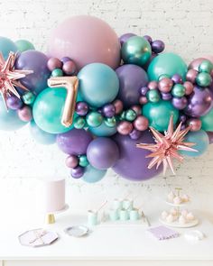 the balloon arch is filled with balloons, stars and confetti for a first birthday party