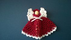 a crocheted angel doll with white wings and a red dress on a blue background