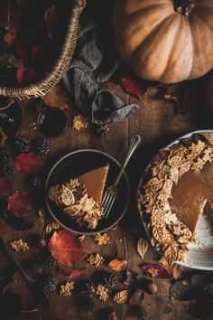 a table topped with a pie covered in frosting next to a basket of pumpkins