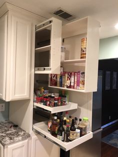 an open cabinet in a kitchen with food on the counter and other items inside it