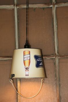 a lamp hanging from the side of a wall with a beer advertisement on it's shade