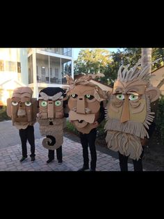 three people wearing cardboard faces with green eyes and long hair standing next to each other