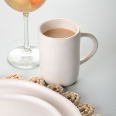 a cup of coffee next to a plate with cookies on it and a glass of wine