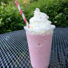 a pink drink with whipped cream on top and a red and white striped straw sticking out of it