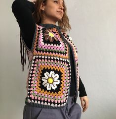 a woman wearing a colorful crocheted vest with flowers on the front and sides