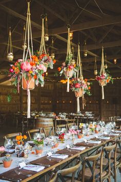 the tables are set up for an event with hanging vases and flower centerpieces