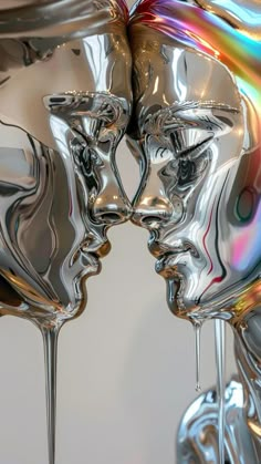 two silver faces are touching each other with their noses covered in liquid droplets, as if they were kissing