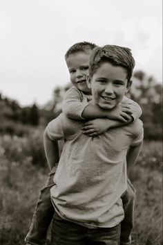 two young boys hugging each other in a field