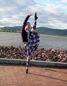 a woman in a kilt dancing by the water