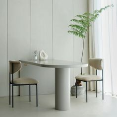 a table with two chairs and a plant in the corner next to it on a white floor