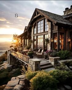 a large house sitting on top of a cliff next to the ocean at sunset or dawn