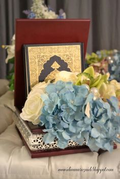 blue and white flowers sitting on top of a wooden box next to a table cloth