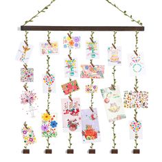 a bunch of cards hanging from a wooden frame on a string with some plants growing out of them