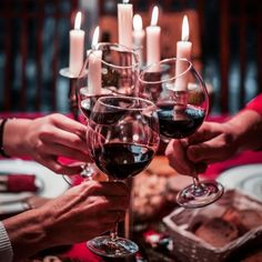 several people are toasting wine glasses with candles in the background