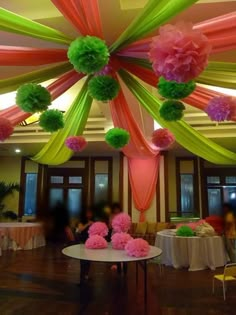 the ceiling is decorated with tissue flowers and pom poms in pink, green, and yellow colors