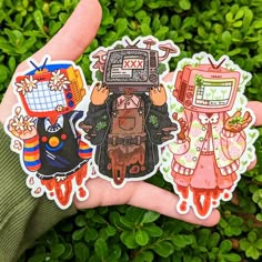 three stickers in the palm of someone's hand with green plants behind them