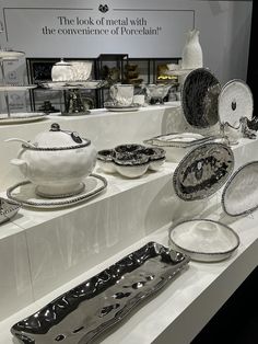 an assortment of silver and white dishes on display