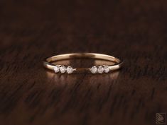 a gold ring with three diamonds on top of a wooden table in front of a dark background